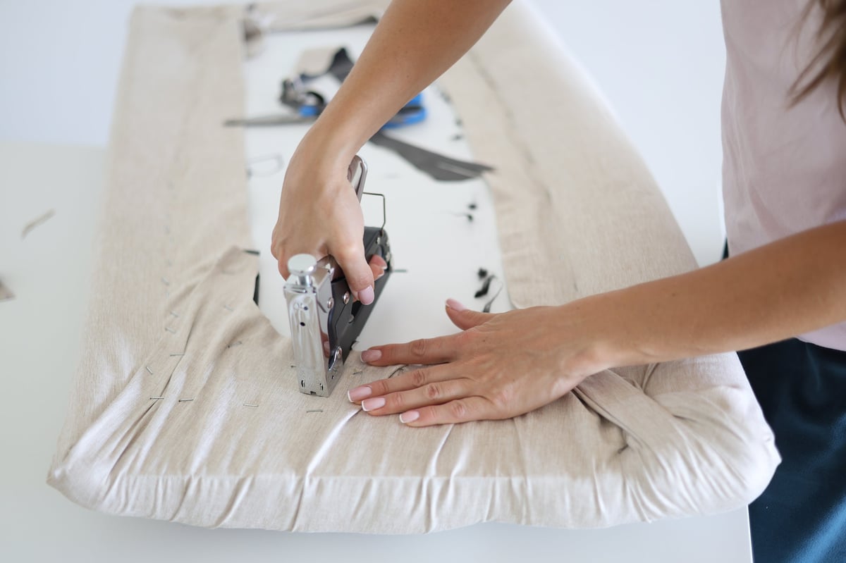 Upholsterer using a staple gun to work marine-grade vinyl onto a boat cushion